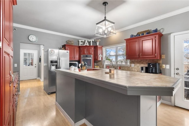 kitchen with a chandelier, stainless steel appliances, tasteful backsplash, and light hardwood / wood-style floors