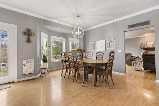 dining room featuring light hardwood / wood-style floors, crown molding, and a notable chandelier