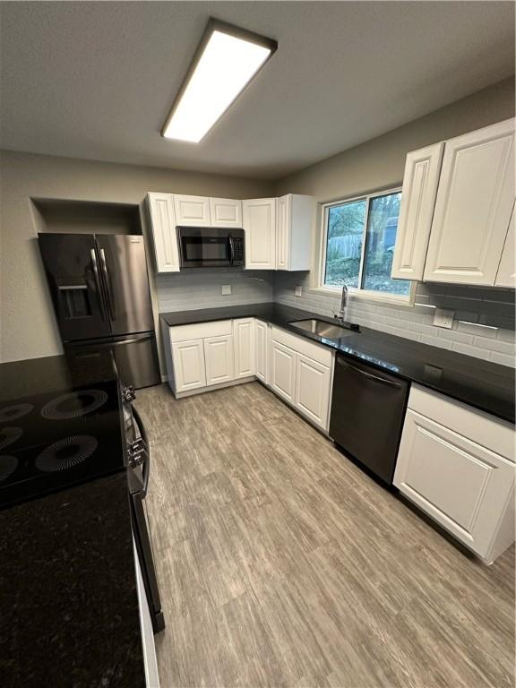 kitchen with white cabinetry, black appliances, and light wood-type flooring