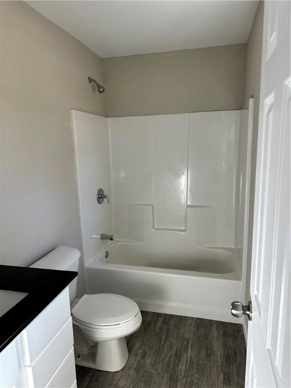 full bathroom featuring toilet, vanity,  shower combination, and hardwood / wood-style flooring