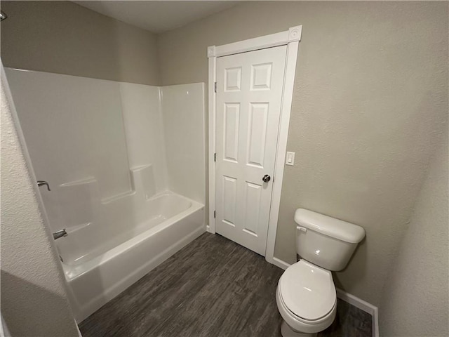 bathroom with washtub / shower combination, hardwood / wood-style floors, and toilet