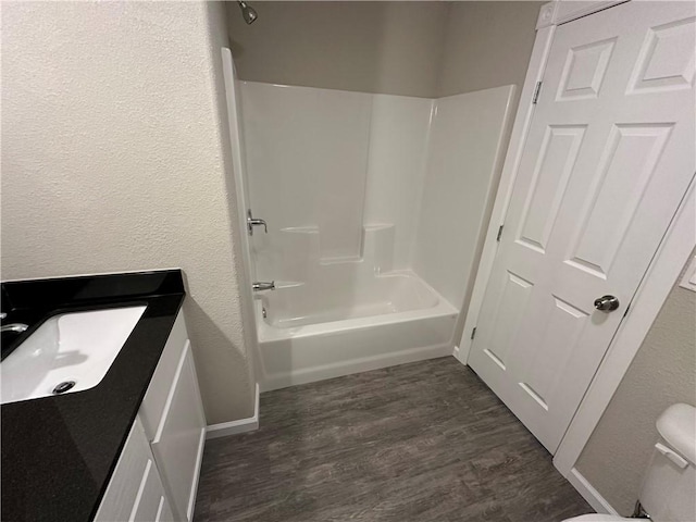 full bathroom with sink, hardwood / wood-style floors, shower / bathing tub combination, and toilet