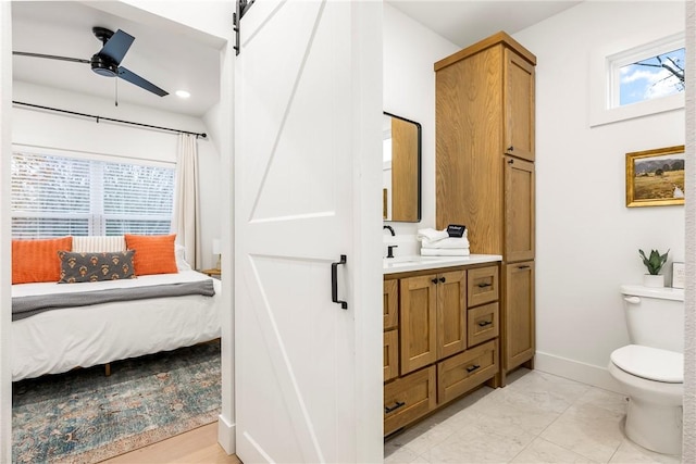 bathroom with toilet, connected bathroom, baseboards, ceiling fan, and vanity