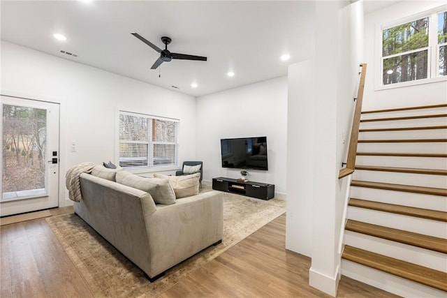 living room featuring recessed lighting, visible vents, light wood-style flooring, and stairs