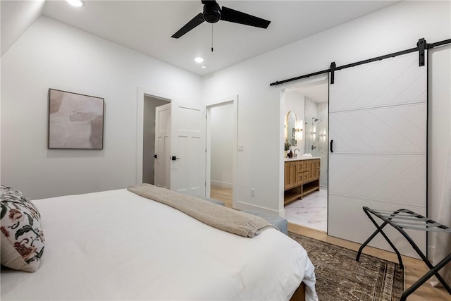 bedroom with recessed lighting, ensuite bath, a barn door, and a ceiling fan