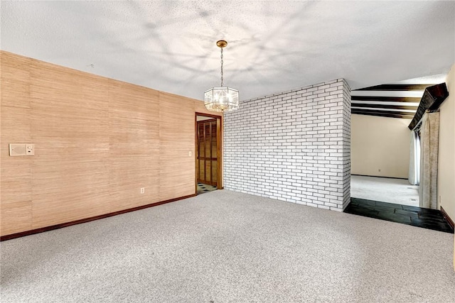 carpeted empty room with a textured ceiling, wooden walls, and vaulted ceiling