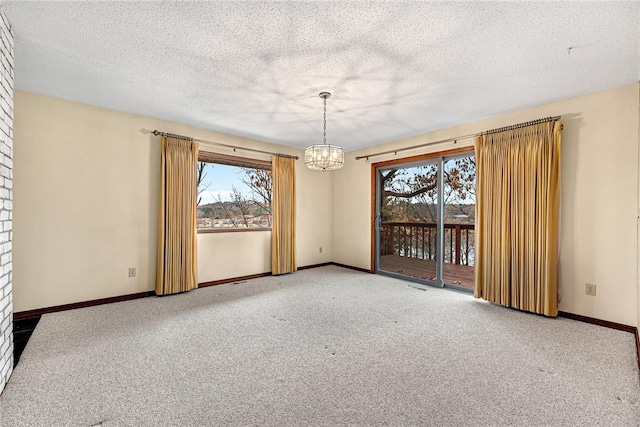 carpeted empty room featuring a chandelier and a textured ceiling