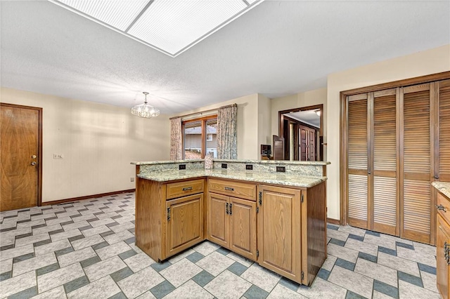 kitchen featuring a notable chandelier, light stone countertops, a textured ceiling, and decorative light fixtures