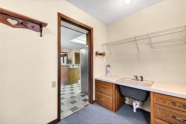 office with sink, built in desk, a textured ceiling, and light carpet