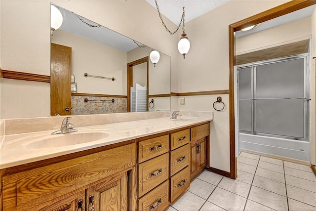 bathroom featuring tile patterned flooring, vanity, bath / shower combo with glass door, and a textured ceiling