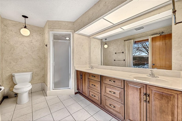 bathroom with vanity, a textured ceiling, toilet, and a shower with shower door