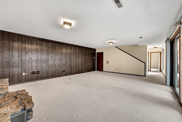 basement with wooden walls, light colored carpet, and a textured ceiling