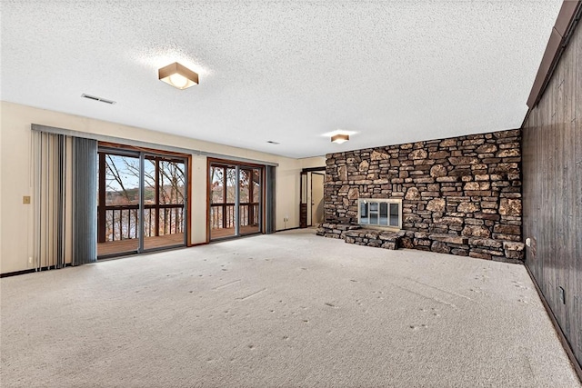 unfurnished living room featuring a textured ceiling, carpet flooring, a fireplace, and wooden walls