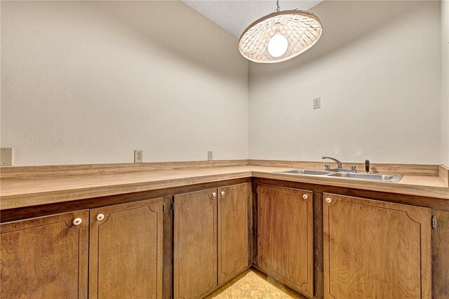 interior space featuring wooden counters, hanging light fixtures, and sink