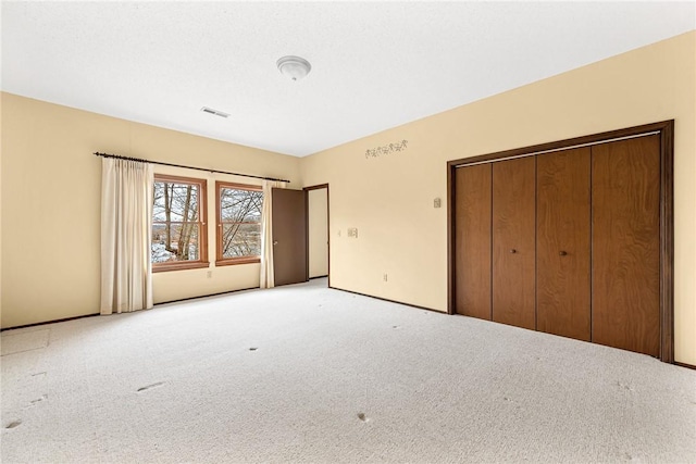 unfurnished bedroom featuring a closet and light colored carpet