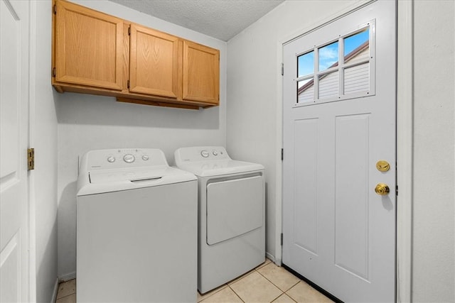 laundry area featuring washer and clothes dryer, cabinets, light tile patterned floors, and a textured ceiling