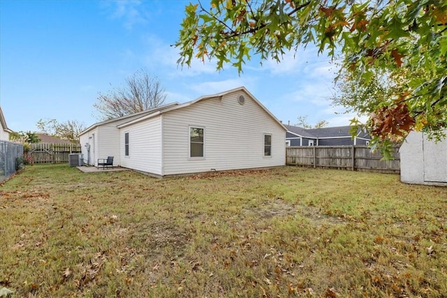 rear view of property featuring central air condition unit and a lawn