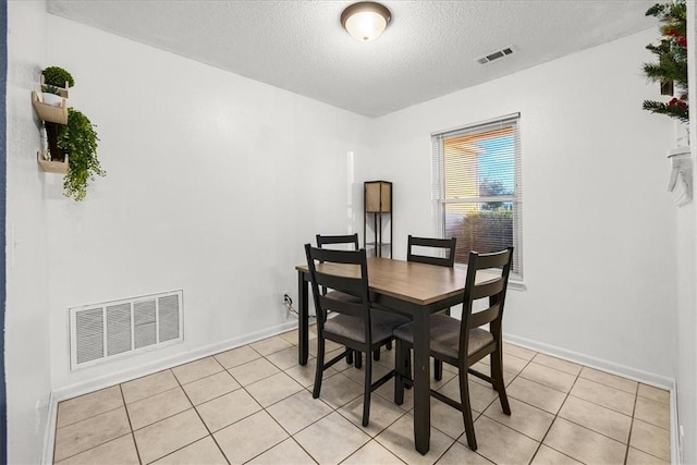 dining space with a textured ceiling and light tile patterned flooring