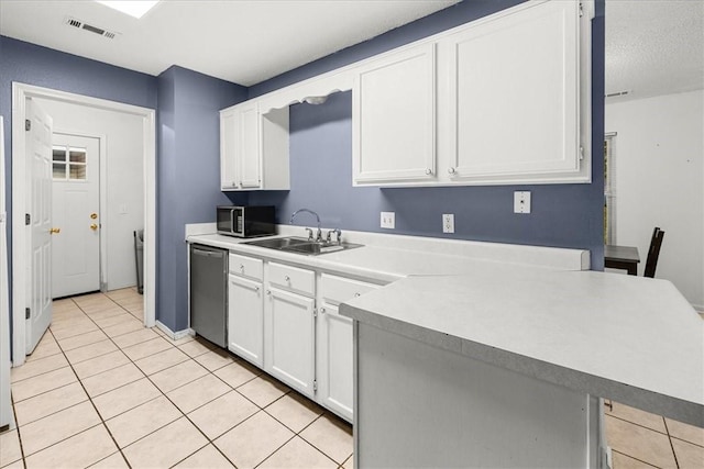 kitchen with kitchen peninsula, stainless steel appliances, sink, light tile patterned floors, and white cabinets