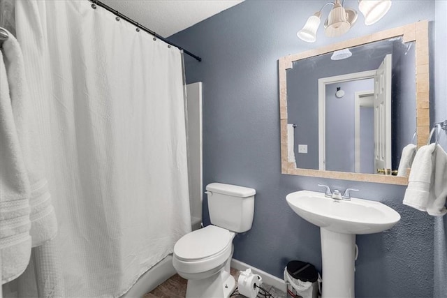 bathroom featuring a shower with shower curtain, a textured ceiling, and toilet