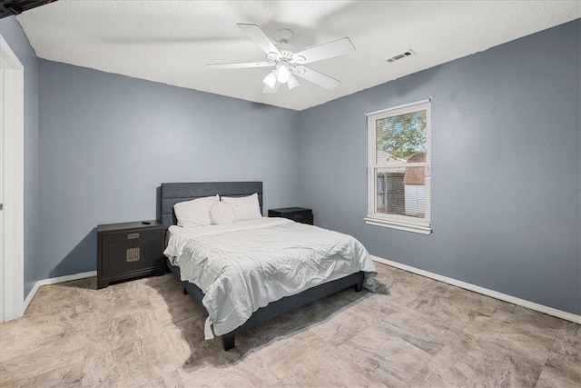 bedroom with ceiling fan and a textured ceiling