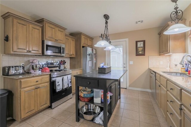 kitchen featuring stainless steel appliances, sink, light stone counters, tasteful backsplash, and pendant lighting