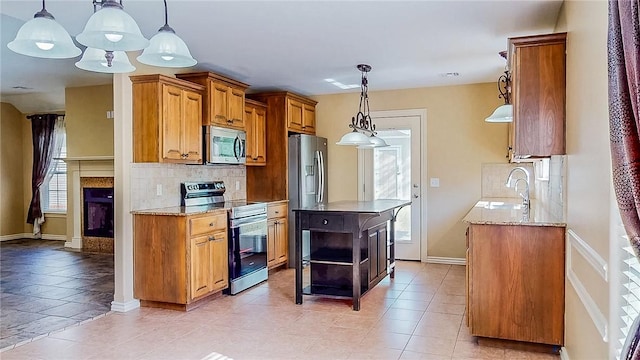 kitchen with stainless steel appliances, decorative backsplash, a kitchen island, light stone counters, and brown cabinets