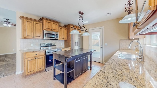 kitchen featuring stainless steel appliances, a sink, light stone countertops, and tasteful backsplash
