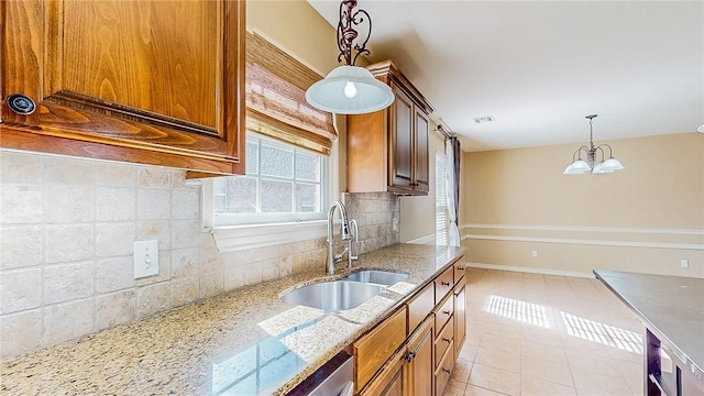 kitchen featuring a sink, decorative backsplash, decorative light fixtures, light stone counters, and light tile patterned floors
