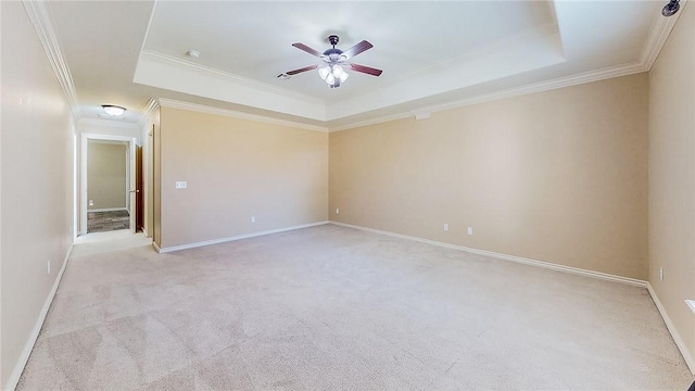 spare room with a tray ceiling, light colored carpet, ceiling fan, and ornamental molding