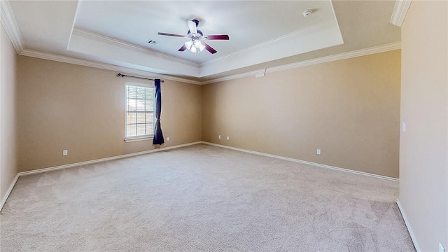 carpeted empty room featuring a raised ceiling, ceiling fan, crown molding, and baseboards