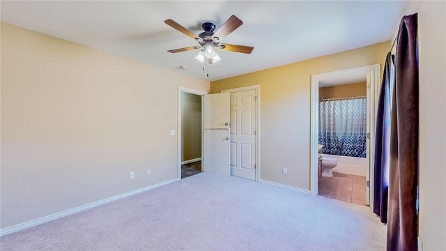 unfurnished bedroom with carpet floors, baseboards, ensuite bathroom, and a ceiling fan