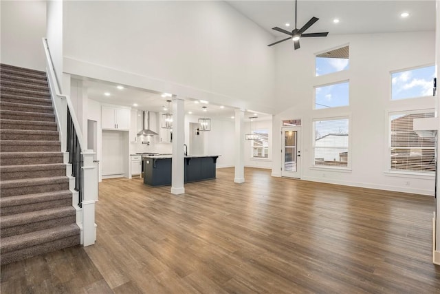 unfurnished living room with dark wood-type flooring, a towering ceiling, and ceiling fan