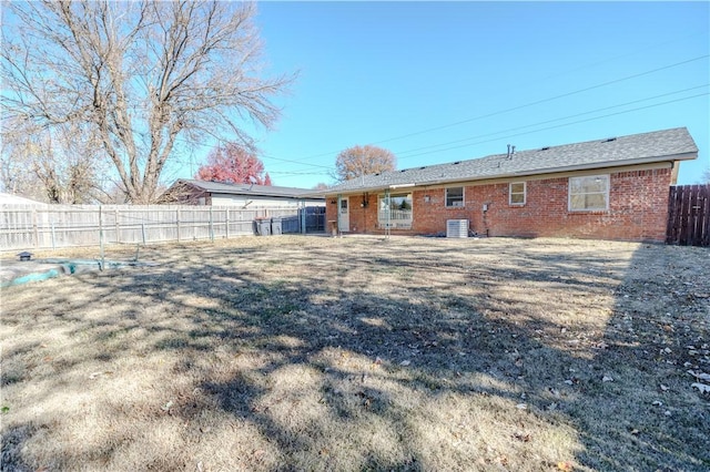 back of house with cooling unit and a lawn