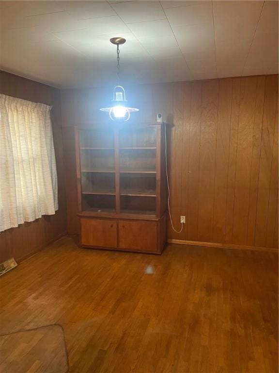 empty room featuring wood-type flooring and wooden walls