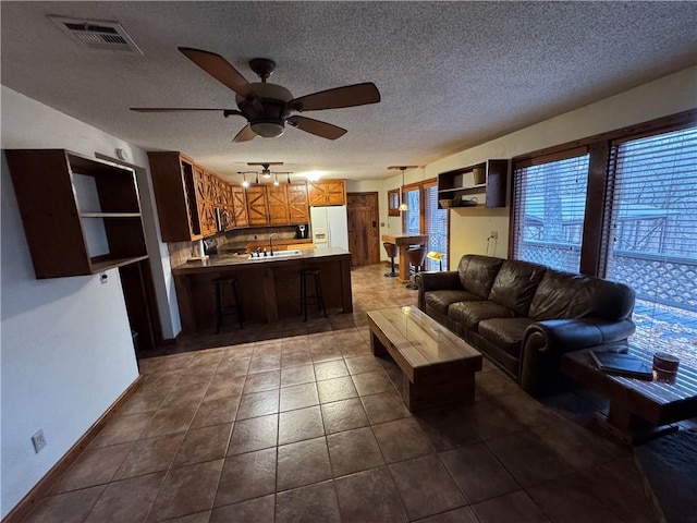 living room featuring tile patterned floors, ceiling fan, sink, and a textured ceiling