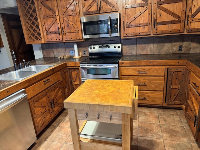 kitchen with backsplash, stainless steel appliances, sink, light tile patterned floors, and butcher block counters