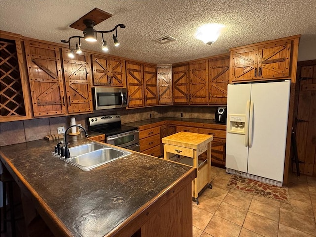 kitchen featuring appliances with stainless steel finishes, a textured ceiling, light tile patterned floors, and sink