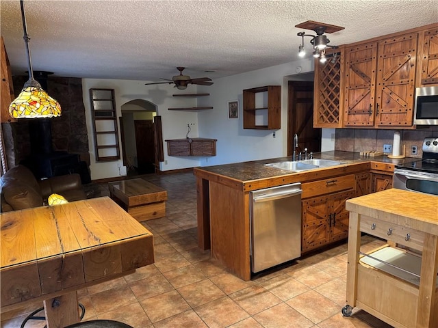 kitchen featuring hanging light fixtures, sink, a textured ceiling, appliances with stainless steel finishes, and tasteful backsplash