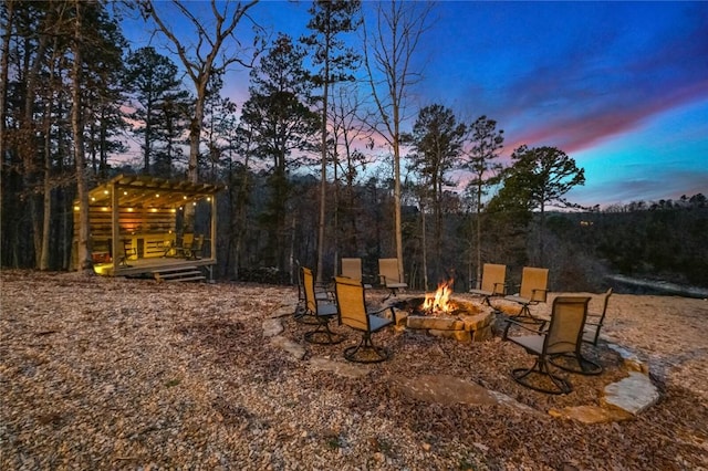 yard at dusk featuring a pergola and a fire pit