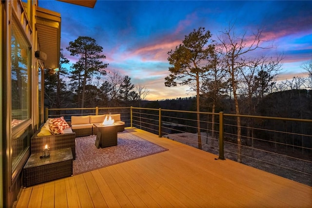 deck at dusk with an outdoor living space with a fire pit