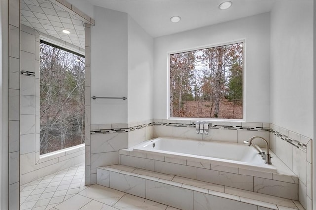 bathroom featuring tile patterned flooring, a relaxing tiled tub, and a wealth of natural light