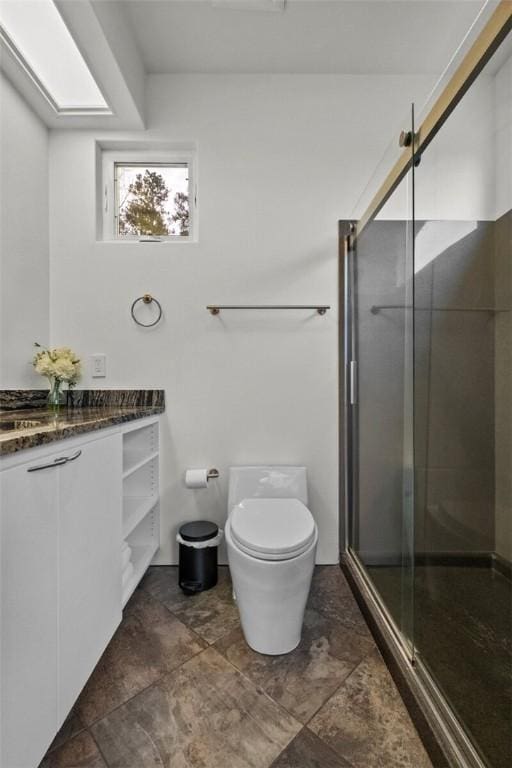 bathroom with a shower with door, vanity, and toilet