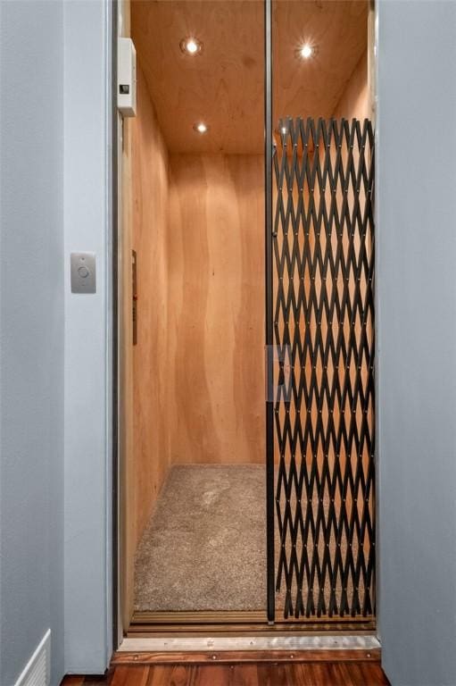 room details with hardwood / wood-style flooring, elevator, and wood walls