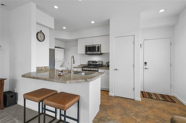 kitchen featuring kitchen peninsula, appliances with stainless steel finishes, a kitchen breakfast bar, sink, and white cabinetry