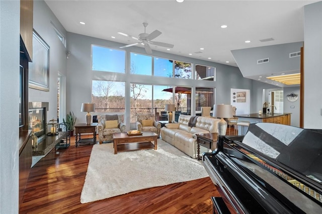 living room featuring ceiling fan, dark hardwood / wood-style flooring, and a towering ceiling