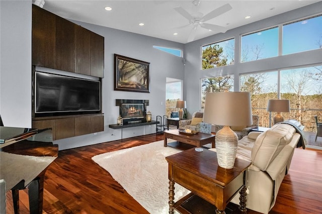 living room featuring ceiling fan, a towering ceiling, and dark wood-type flooring