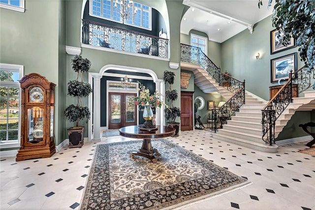 tiled entryway featuring ornate columns, french doors, rail lighting, and a high ceiling