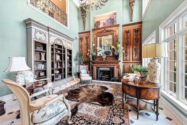 living area with a towering ceiling, a high end fireplace, and a chandelier