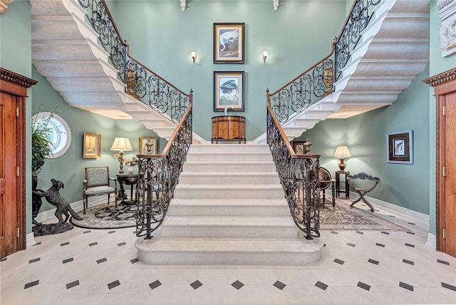 stairs with tile patterned floors and a towering ceiling